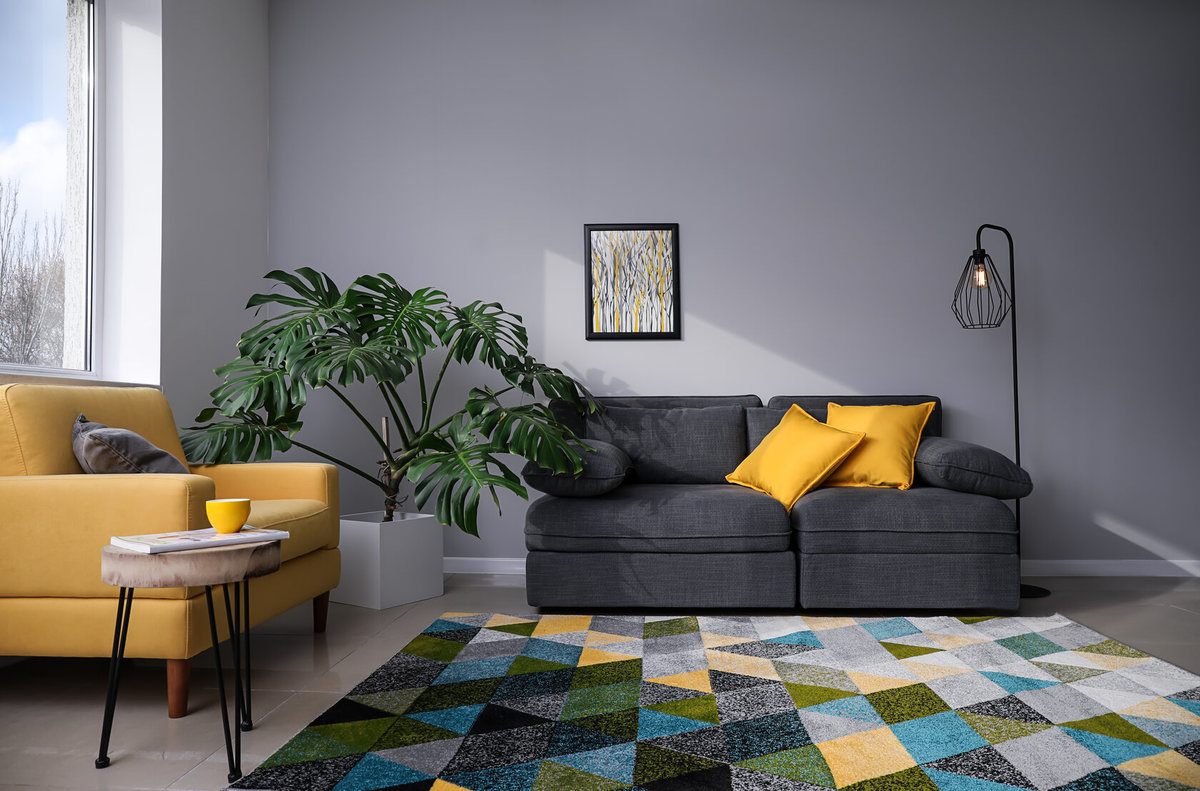 Stylish living room with grey walls and couch, yellow cushions and a rug