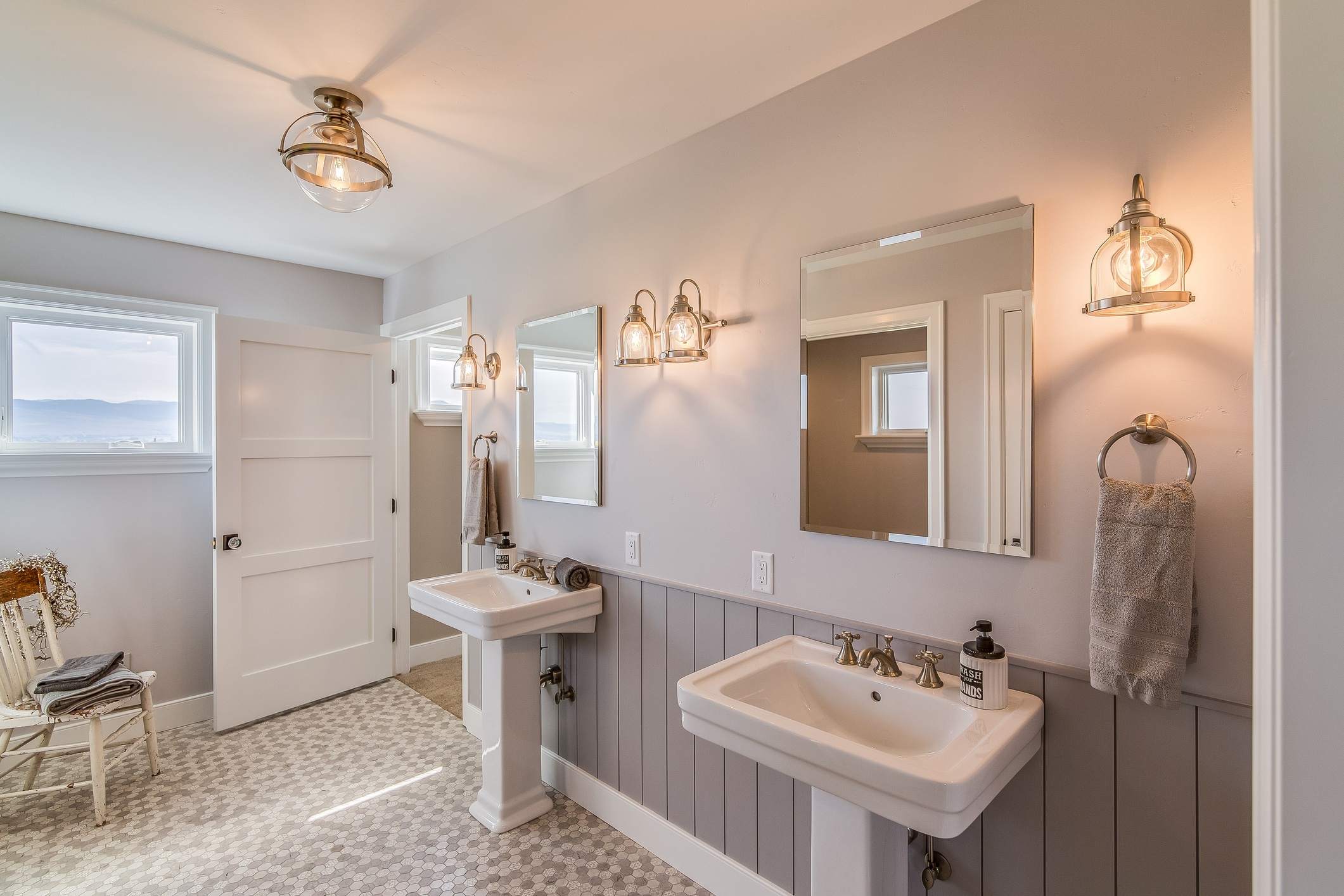 Double pedestal sinks in renovated bathroom with soft pink walls.
