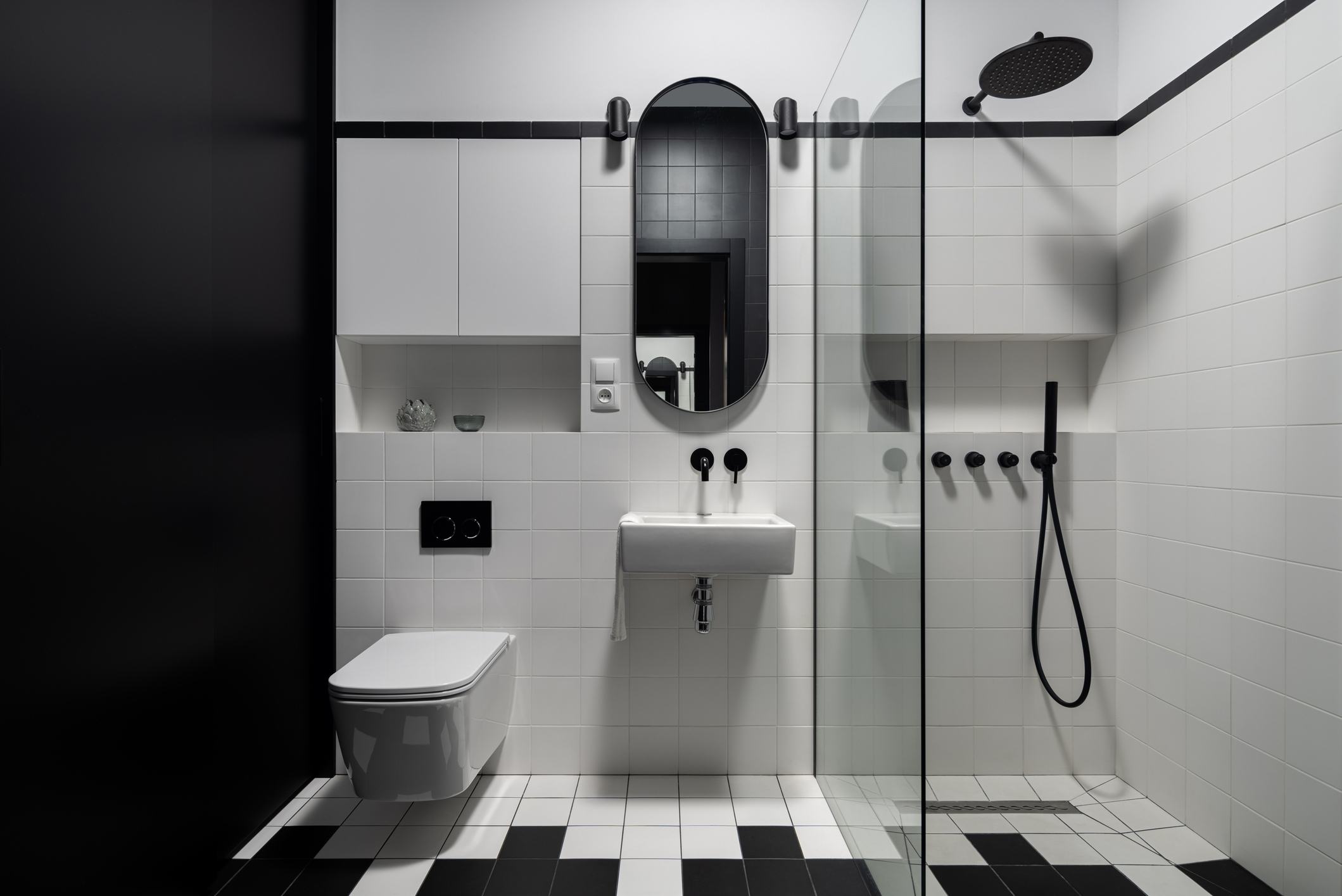 Black and white modern bathroom with square tiles and black accent fixtures.