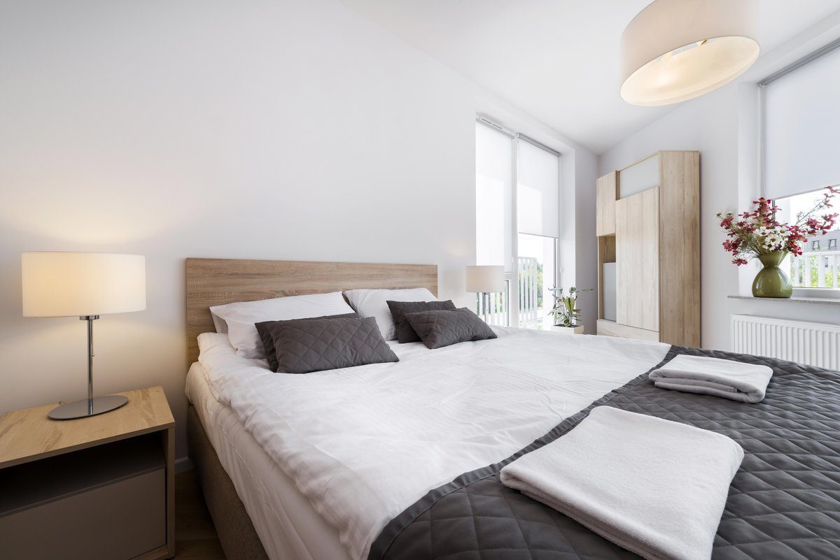 Modern Bedroom With a Bed, Nightstand Lamp, and Wooden Closet