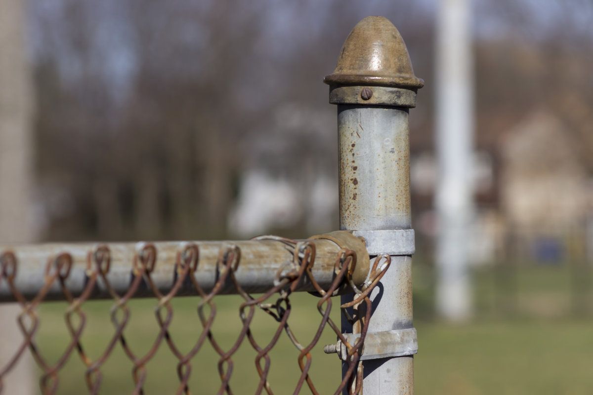 Rusty chain link fence post