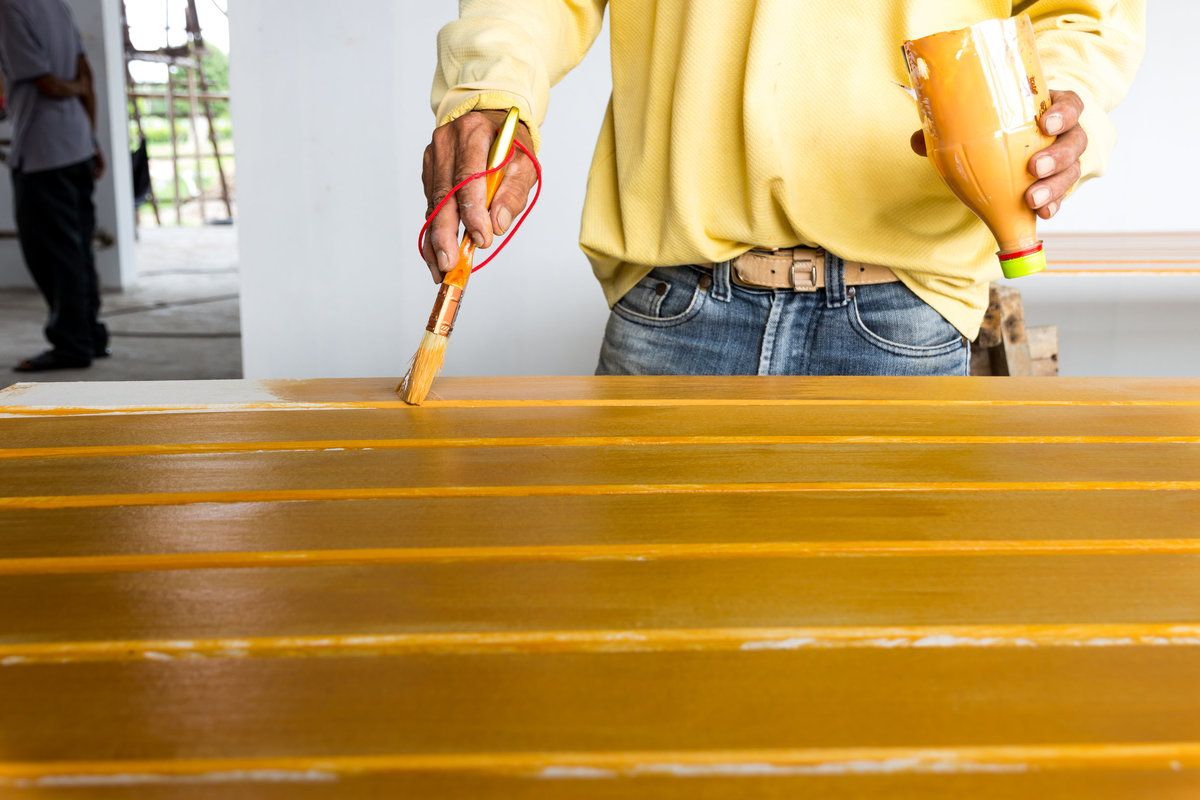 Painter Painting Fiber Cement Siding Boards in Yellow