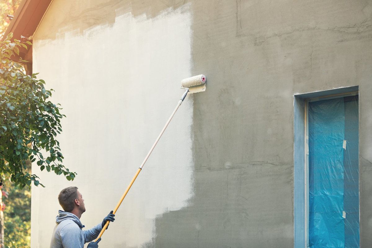 House Painter Painting Building Exterior With a Paint Roller