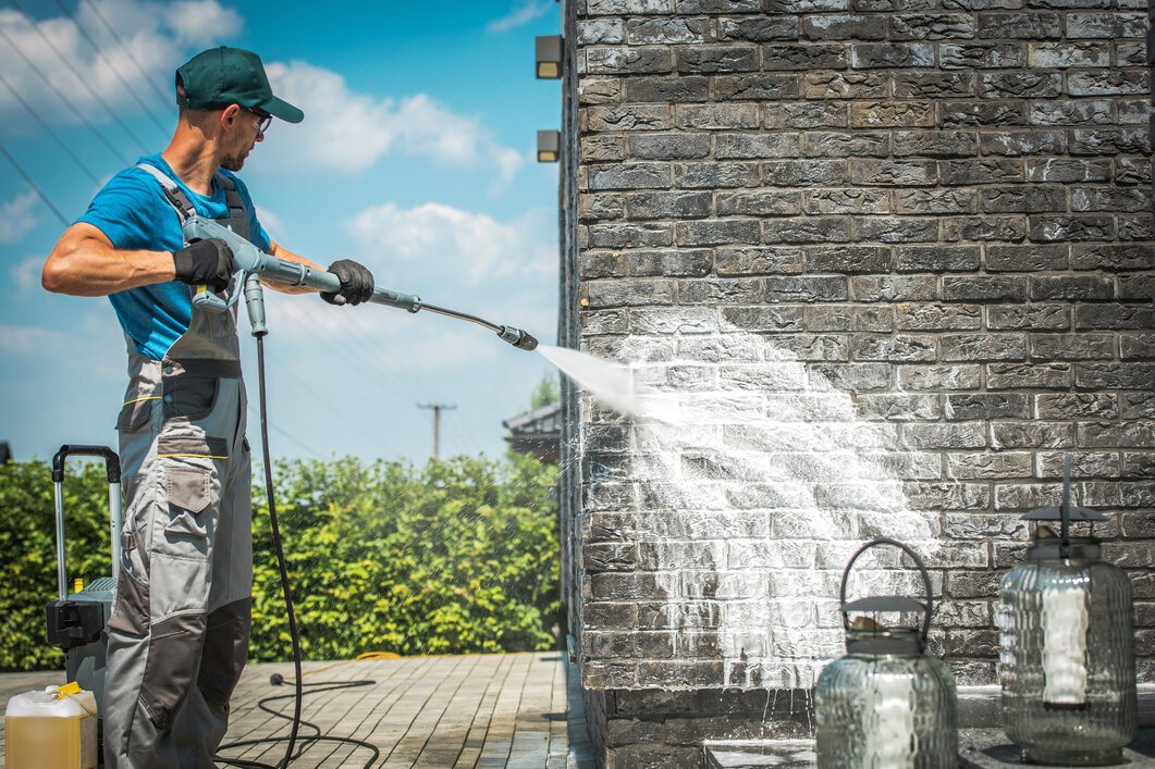 Contractor Pressure Washing a Brick Home